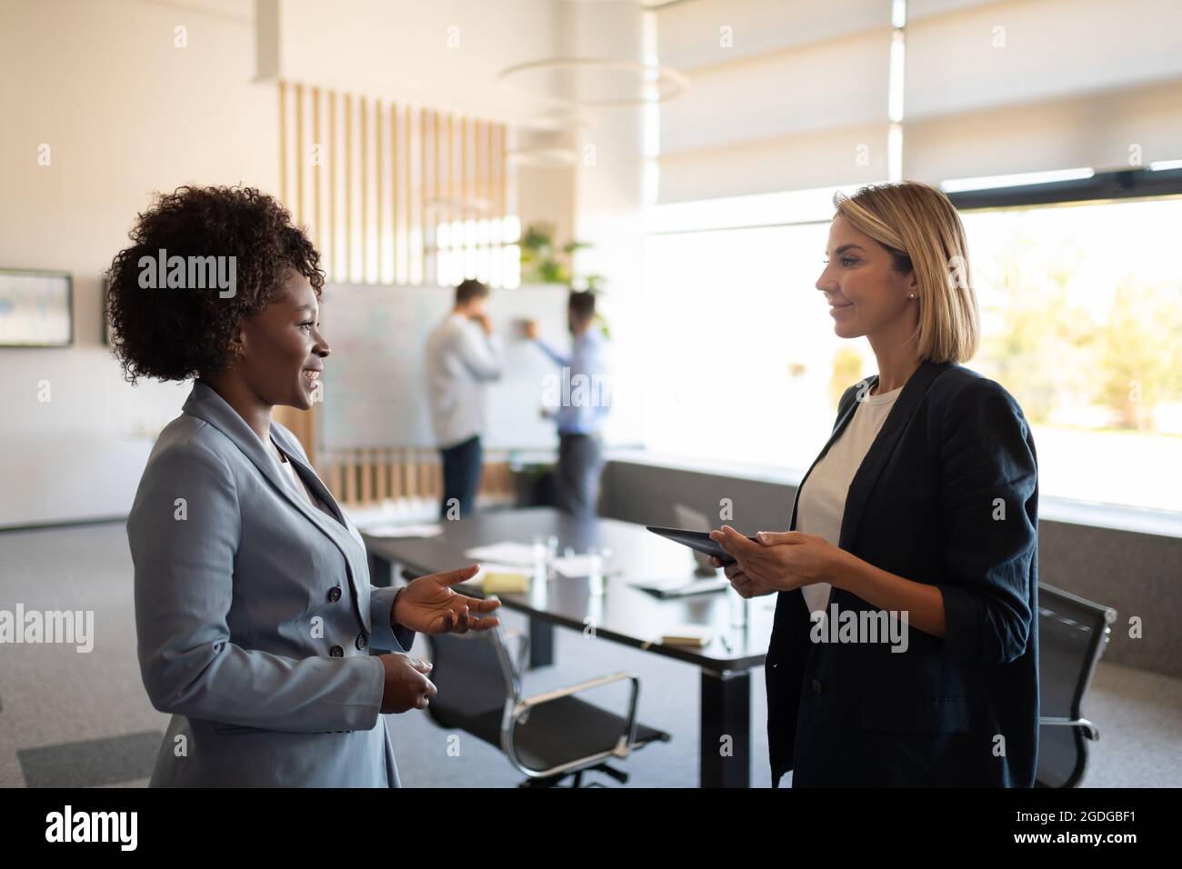 Glad diverse female managers smiling and discussing project during break Stock Photo