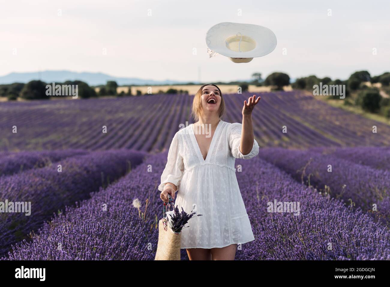 Pregnant woman throwing her hat in the air in lavender fields. Stock Photo