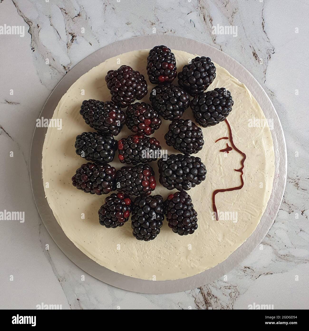 Cheesecake with blackberries and chocolate drawing of girl face Stock Photo