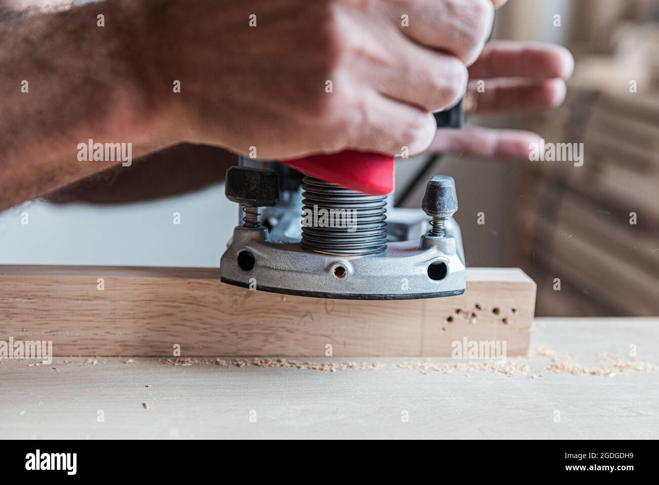 Closeup the male hand processes a wooden board an electric jointer