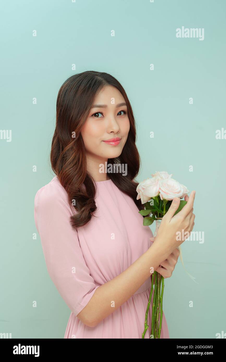 beautiful young woman with a bouquet of roses flowers on a light ...