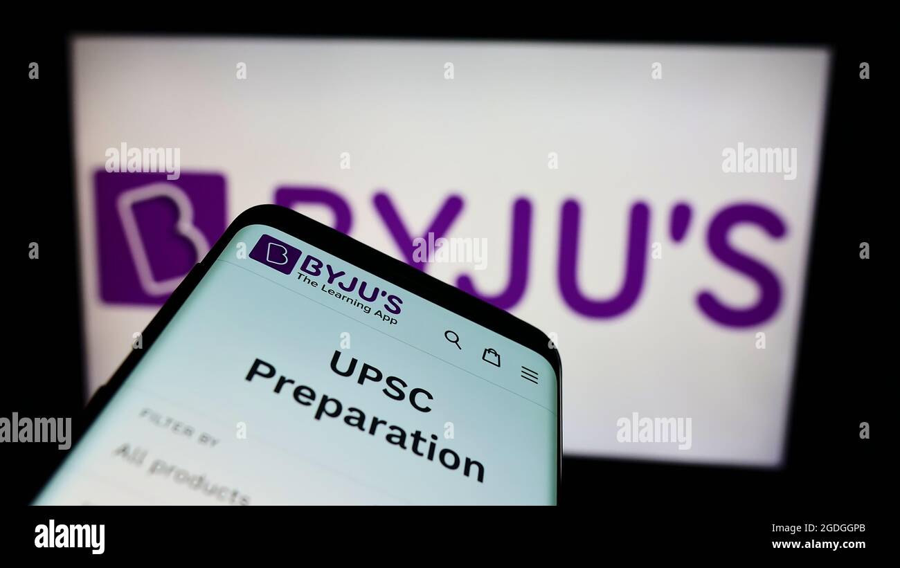Cellphone with webpage of Indian education software company Byju’s on screen in front of business logo. Focus on top-left of phone display. Stock Photo