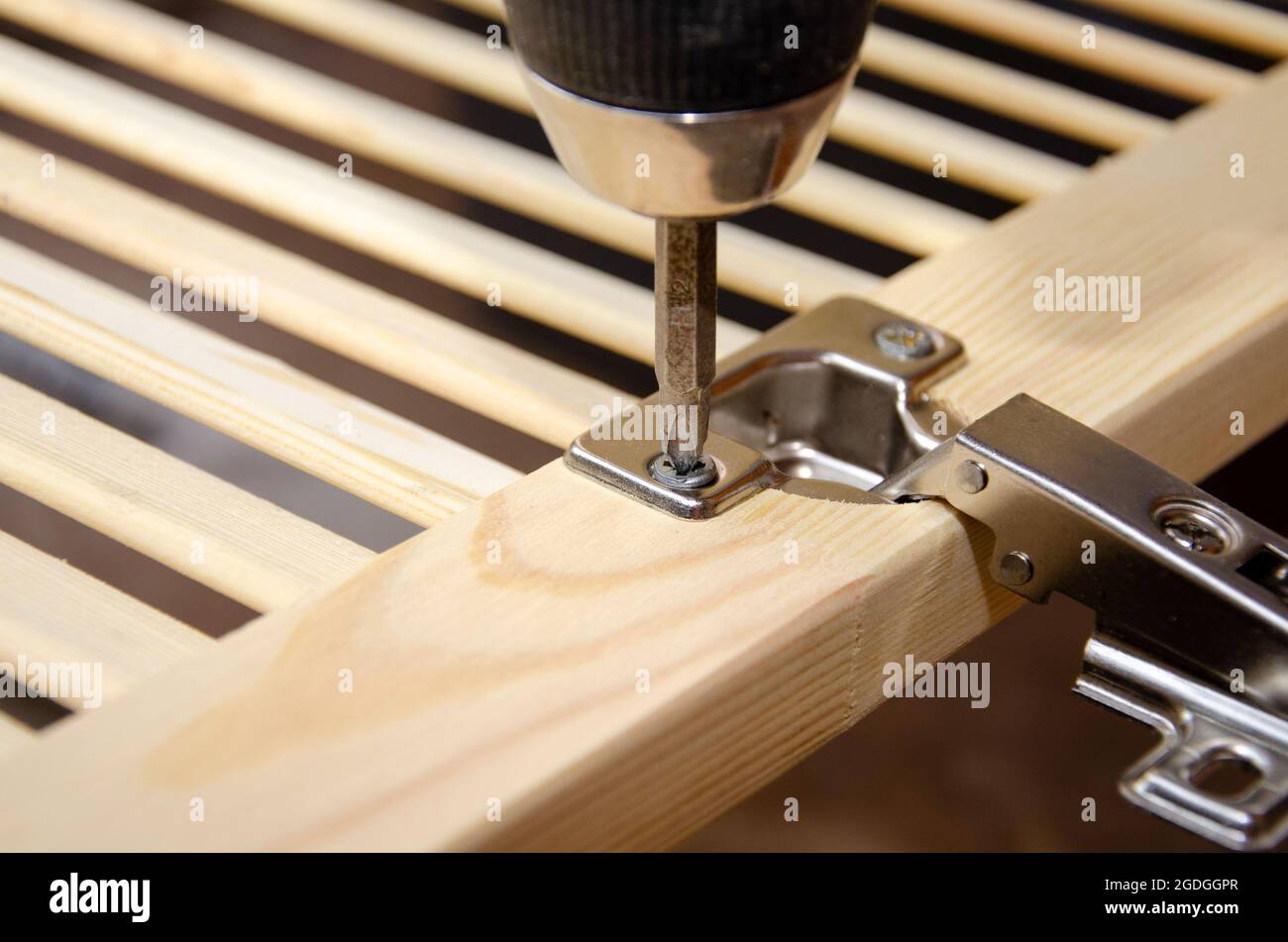 Twisting the selftapping screw into the door hinge with a screwdriver