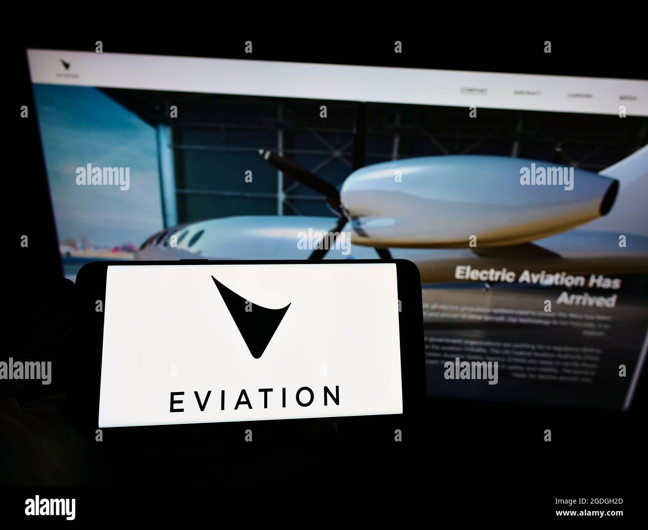 Person holding smartphone with logo of electric aircraft company Eviation Aircraft Ltd. on screen in front of website. Focus on phone display. Stock Photo