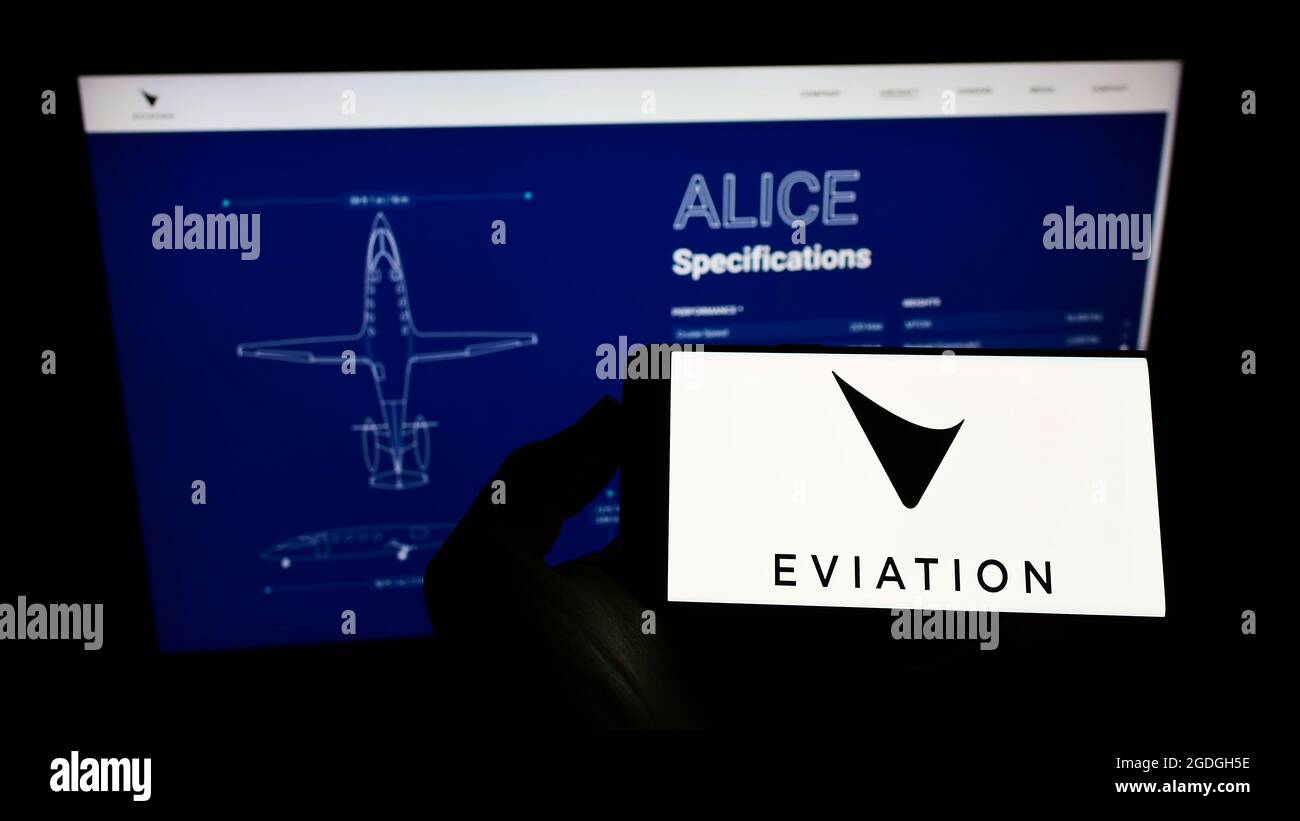 Person holding cellphone with logo of electric aircraft company Eviation Aircraft Ltd. on screen in front of website. Focus on phone display. Stock Photo