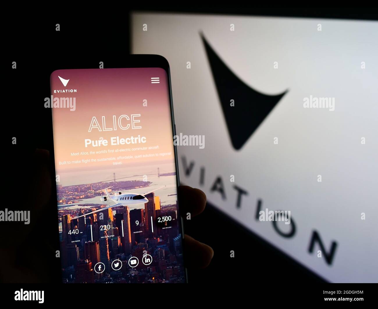 Person holding smartphone with website of electric aircraft company Eviation Aircraft Ltd. on screen with logo. Focus on center of phone display. Stock Photo