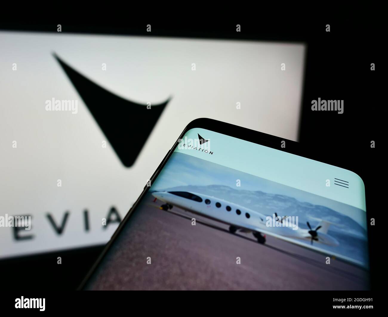 Cellphone with webpage of electric aircraft company Eviation Aircraft Ltd. on screen in front of business logo. Focus on top-left of phone display. Stock Photo