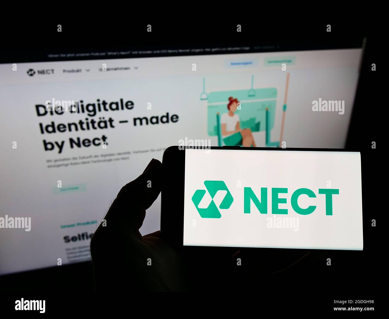 Person holding smartphone with logo of German identity verification company Nect GmbH on screen in front of website. Focus on phone display. Stock Photo