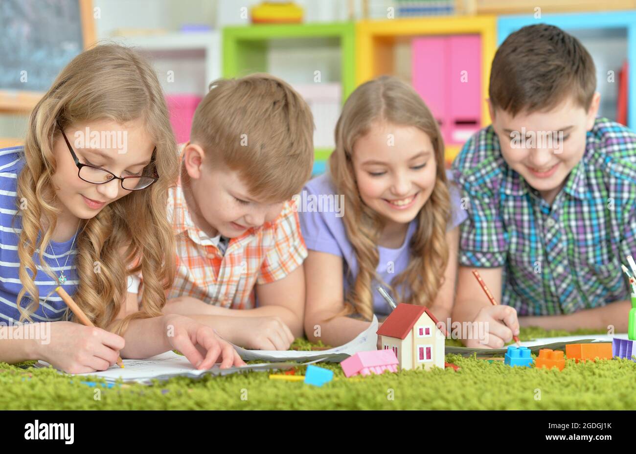 Children lying on floor drawing with pencils Stock Photo - Alamy