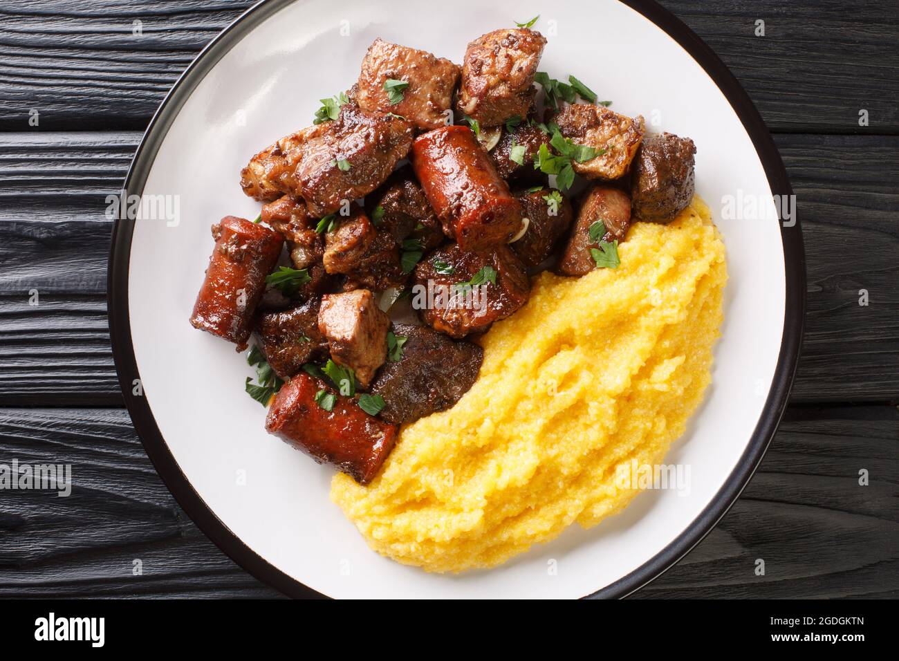Traditional romanian dish pomana porcului assortment of pork meat, sausages with mamaliga close-up in a plate on the table. Horizontal top view from a Stock Photo