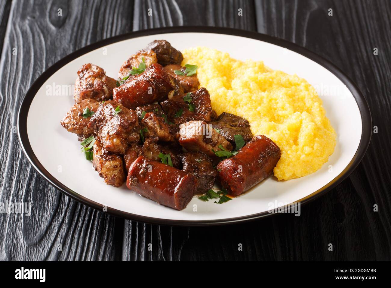 Delicious fried pork, sausages and offal with garlic served with corn porridge close-up in a plate on the table. horizontal Stock Photo