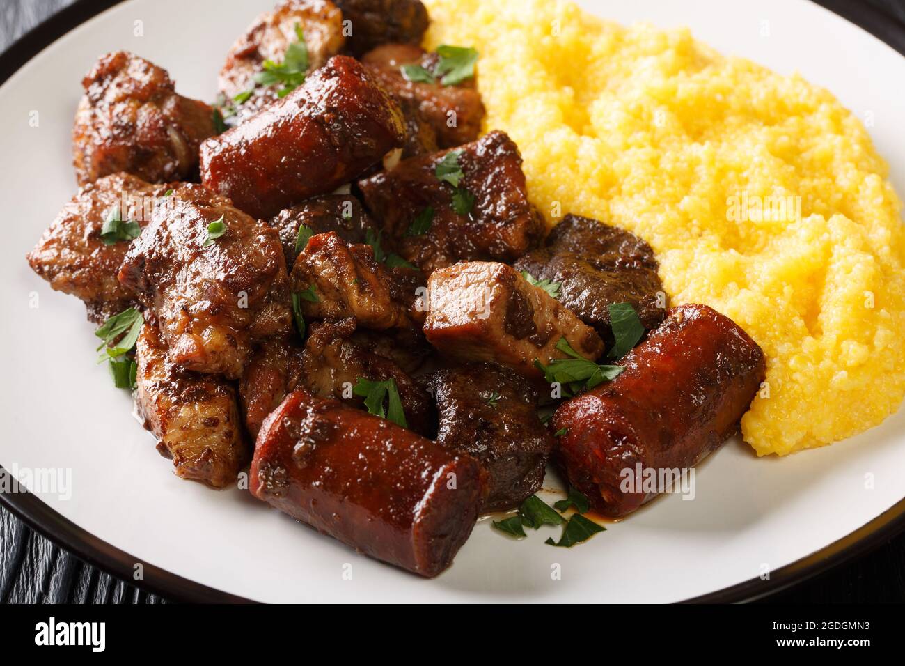 Traditional romanian dish pomana porcului assortment of pork meat, sausages with mamaliga close-up in a plate on the table. Horizontal Stock Photo