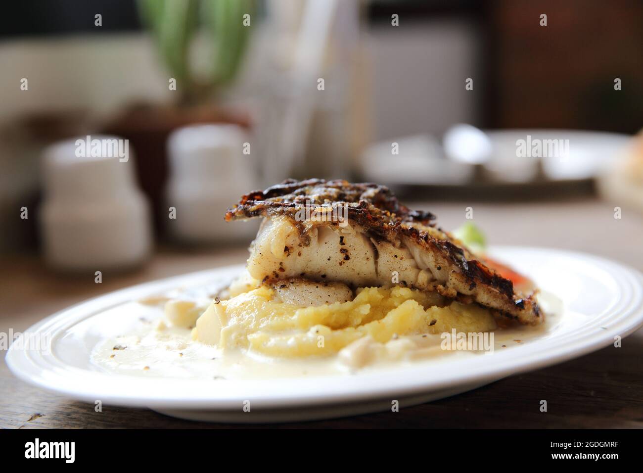 Grill sea bass fillets with crushed potatoes Stock Photo - Alamy