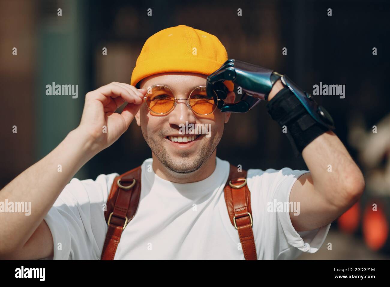 Young disabled man portrait put on yellow glasses with artificial prosthetic bionic robotic hand Stock Photo