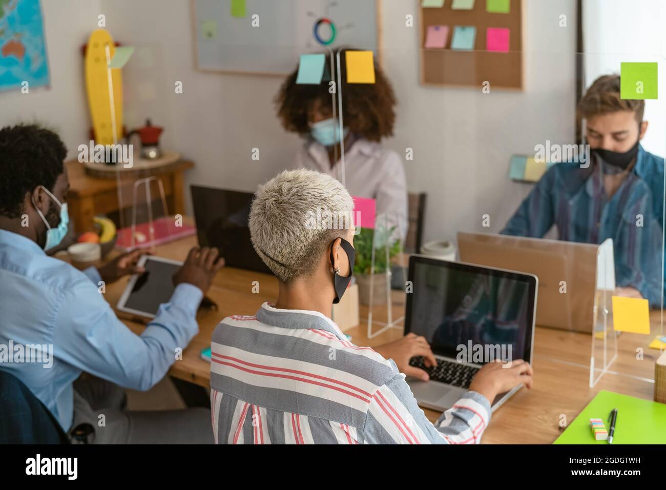 Young multiracial people using computer in co-working creative space while wearing face mask - Health and business technology concept Stock Photo
