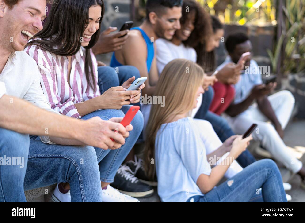 Young multiracial group of friends using mobile smartphone sitting on stairs - Youth millennial lifestyle concept Stock Photo