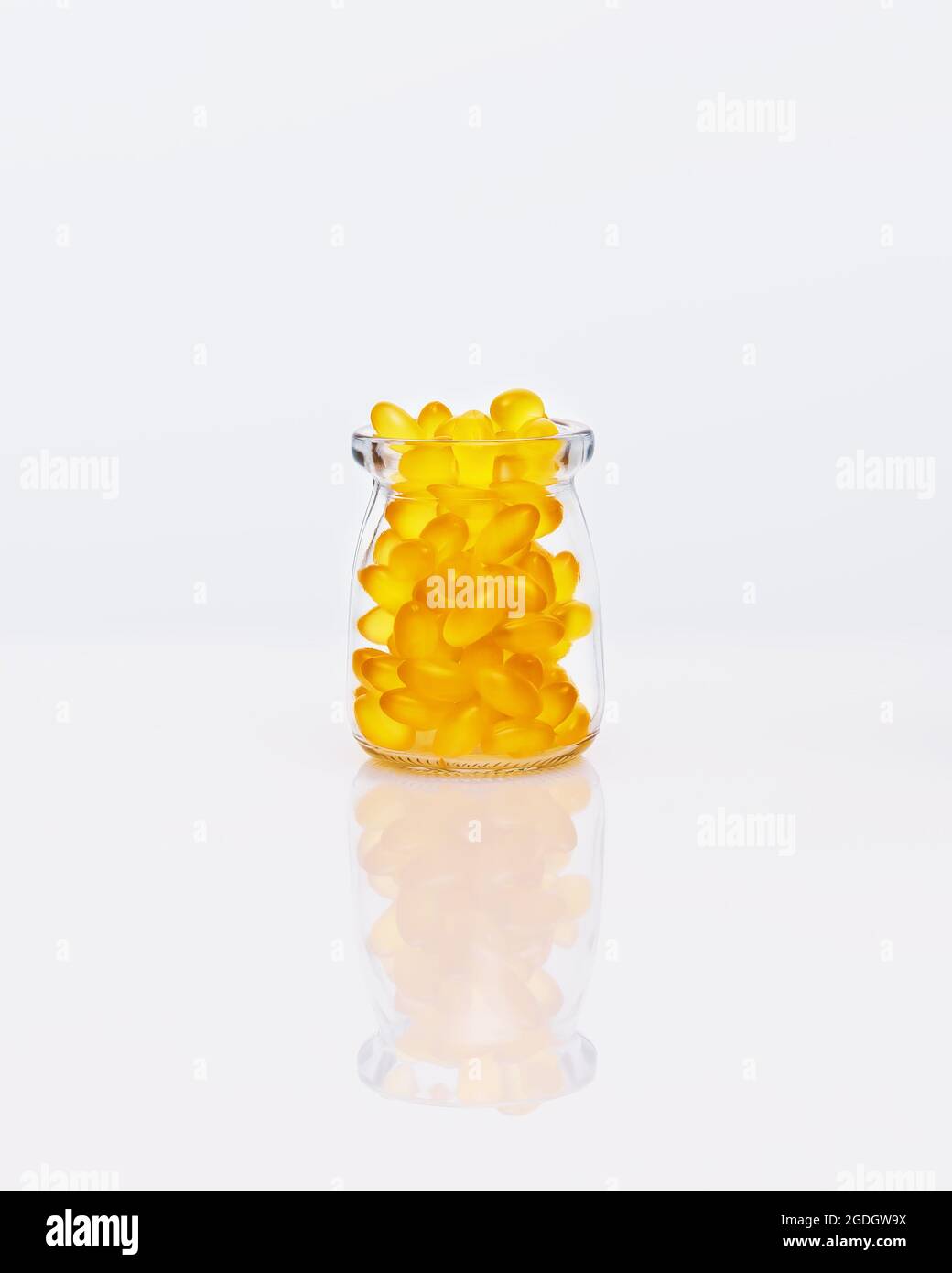 Fish oil, yellow, gelatin capsules in a glass bottle on a white table