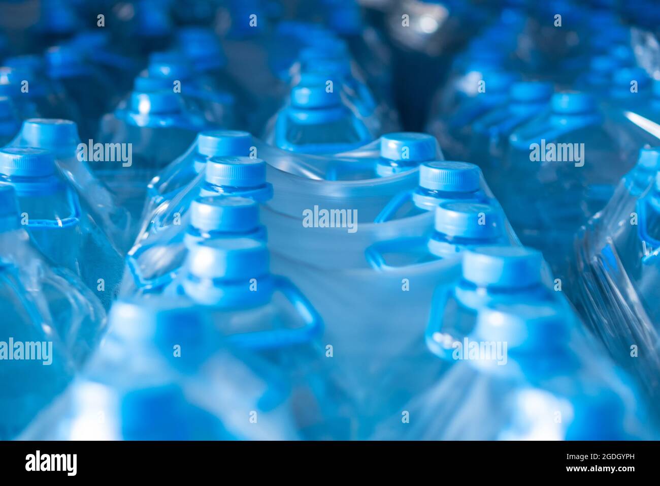 Packaged blue five-liter plastic bottles in the finished product warehouse. Food production Stock Photo