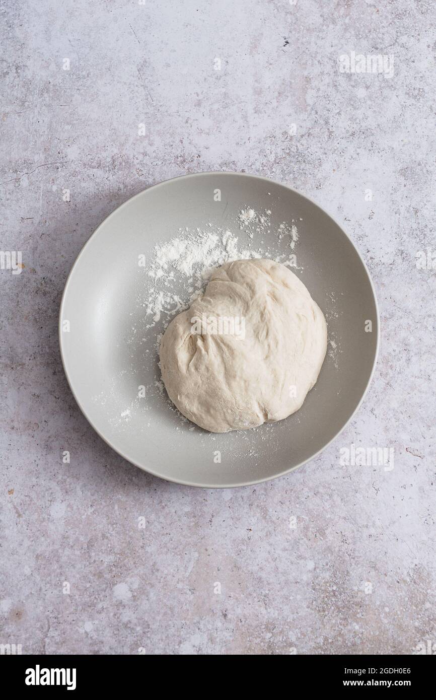 Bowl with ball of floured raw pizza or bread dough. Stock Photo