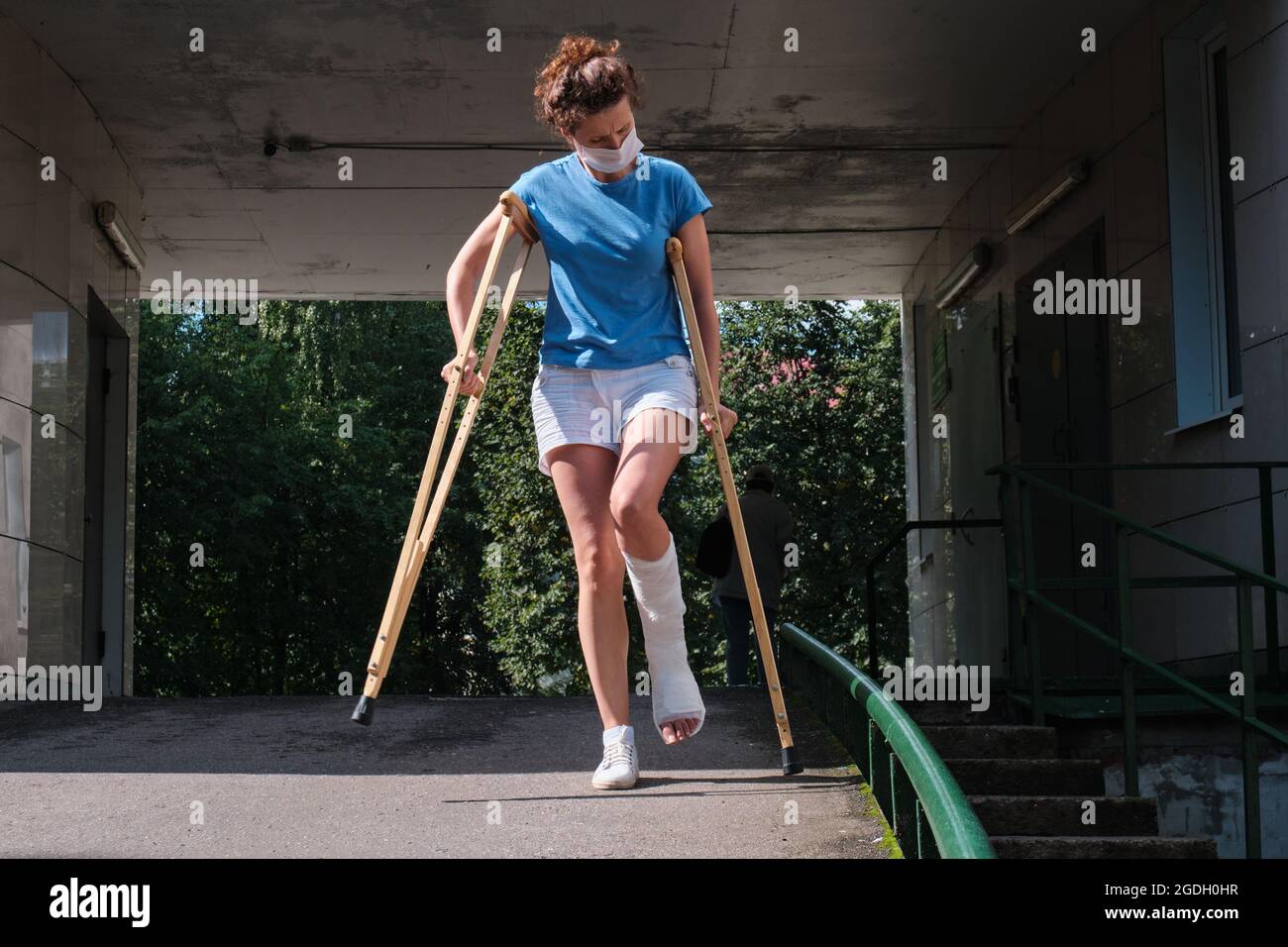 A woman with a broken leg walks down a ramp using orthopedic crutches Stock Photo Alamy