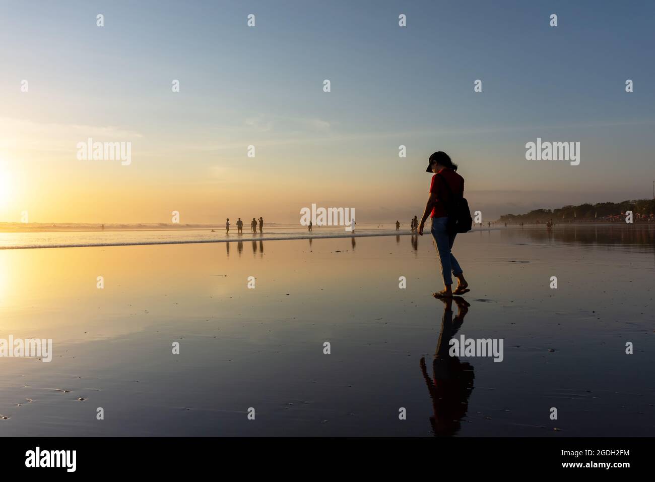 Kuta, Indonesia - September 14, 2018: Silhouette of woman strolling and enjoying sunset at Seminyak beach in Bali. It is one of tourists attraction in Stock Photo