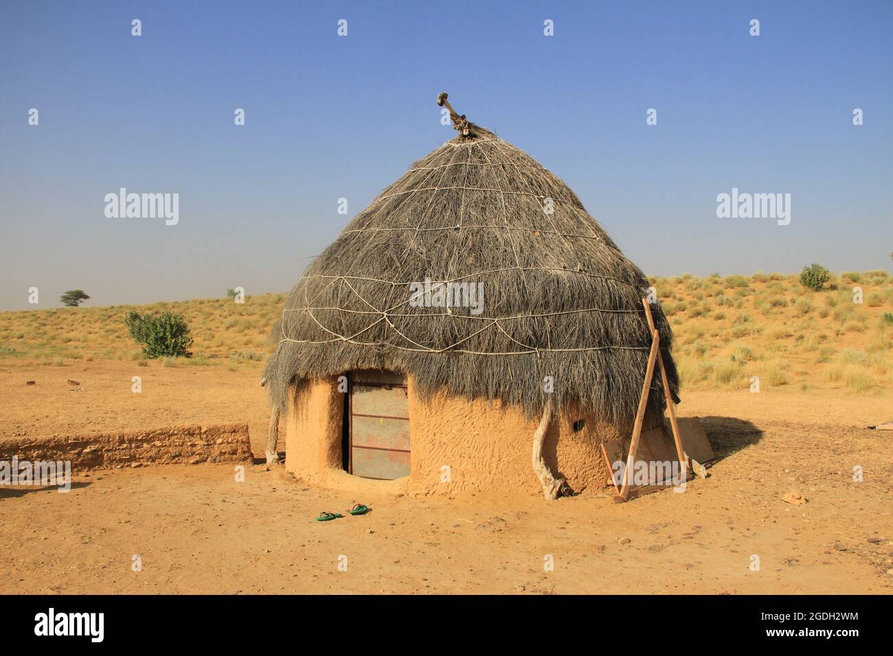 A photo of a traditional thatched roof clay and mud hut and home on a clear sunny blue sky day in Thar desert in Rajasthan, India Stock Photo