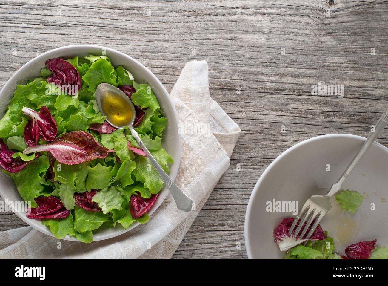 Healthy red and green lettuce salad meals on wooden table background. Eating fresh radicchio and young lettuce with dressing sauce Stock Photo