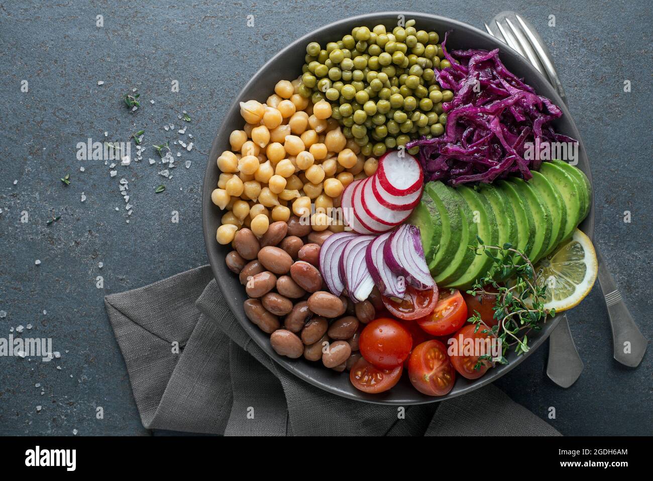 Healthy vegan lunch bowl. Avocado, chickpeas, tomato, red cabbage, green peas, red onion and radish vegetables salad. Healthy balanced vegetarian food Stock Photo
