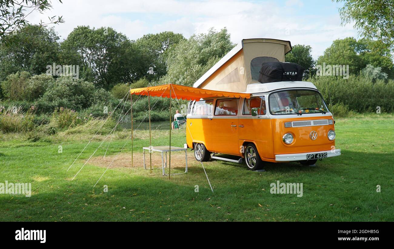 Classic  Orange  Volkswagen  Camper Van parked on Camp Site  by river with top up and Awning . Stock Photo