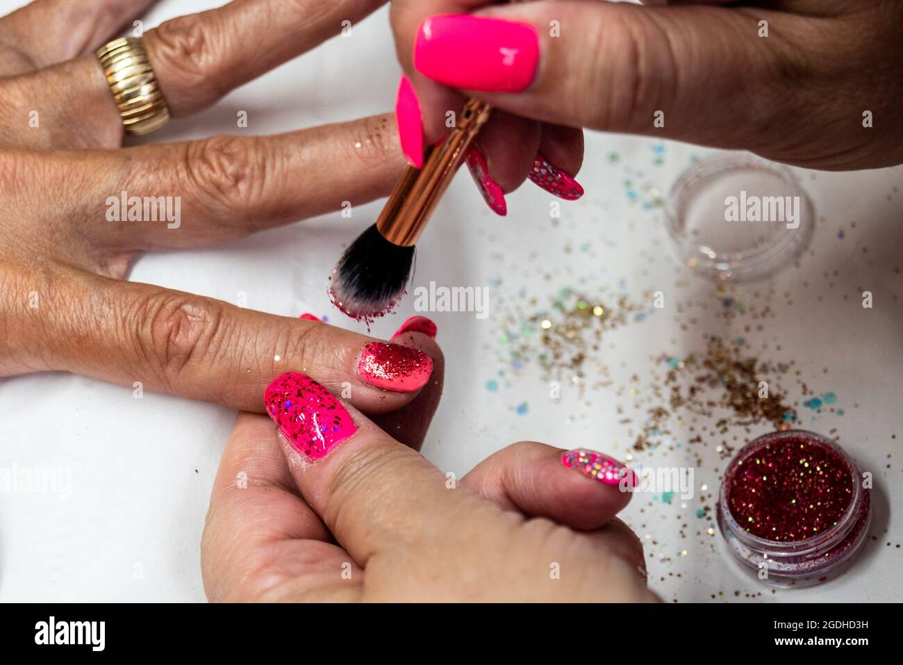 Application of soft gel nail treatment by a nail technician. Nail salon.  Pink gel with glitter. Self employed working from home, authentic situation  Stock Photo - Alamy