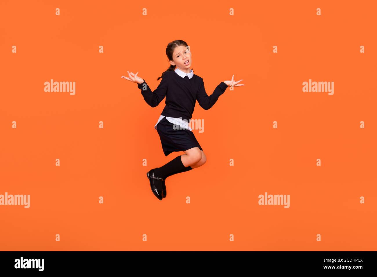 Full length photo of little brown braids haired girl jump shrug shoulders wear long socks