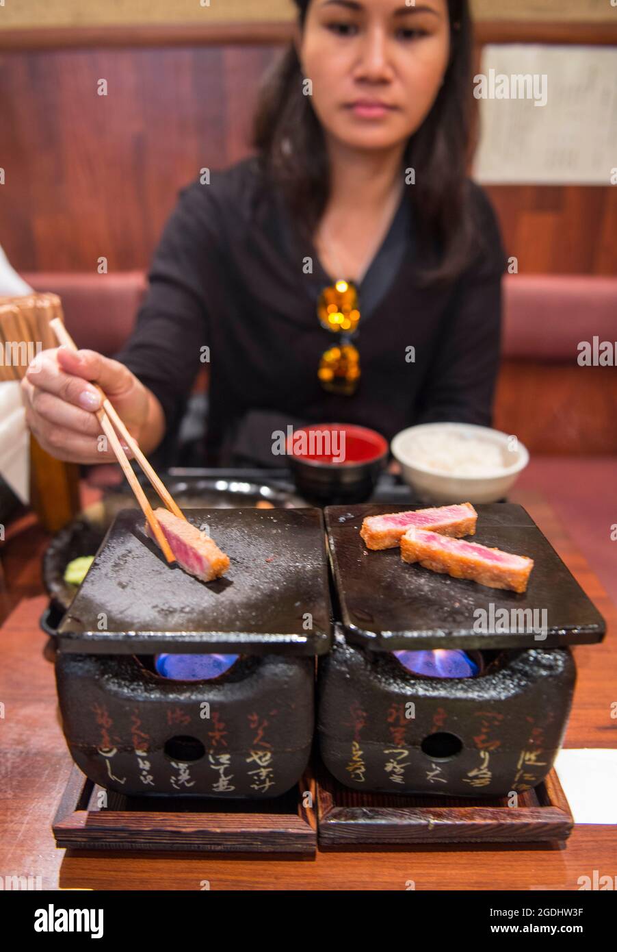 woman cooking beef katsu on traditional Japanese clay stove Stock Photo