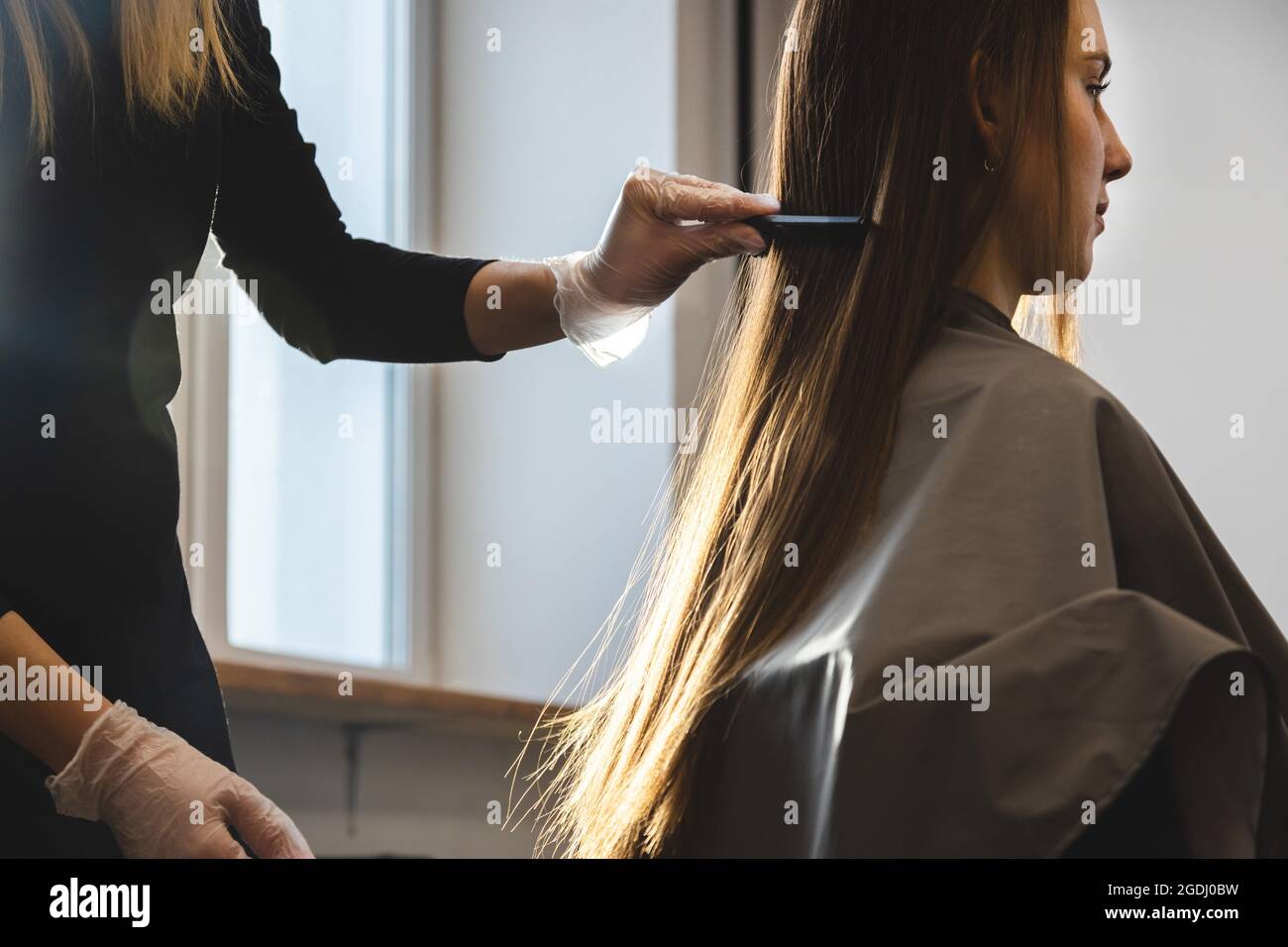 Master hairdresser combs the girl's hair after washing and before