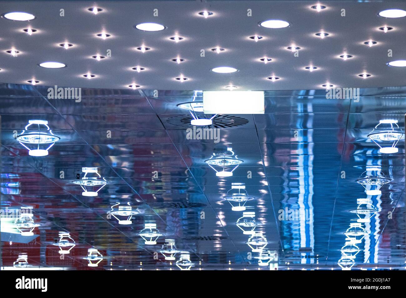 Ceiling lamps are reflected in glass, creating blue light with many structures. Stock Photo