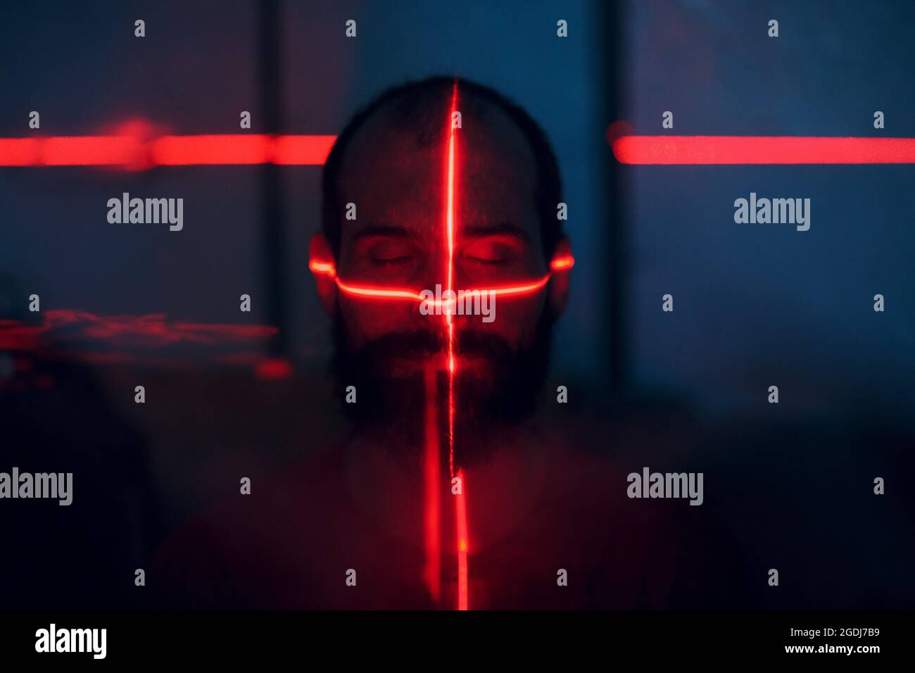 Man in dark with face illuminated by scan red laser on contour. Stock Photo