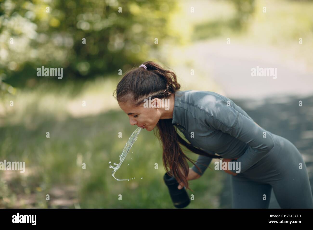 Tired runner woman jogger drinking bottled water after jogging Stock