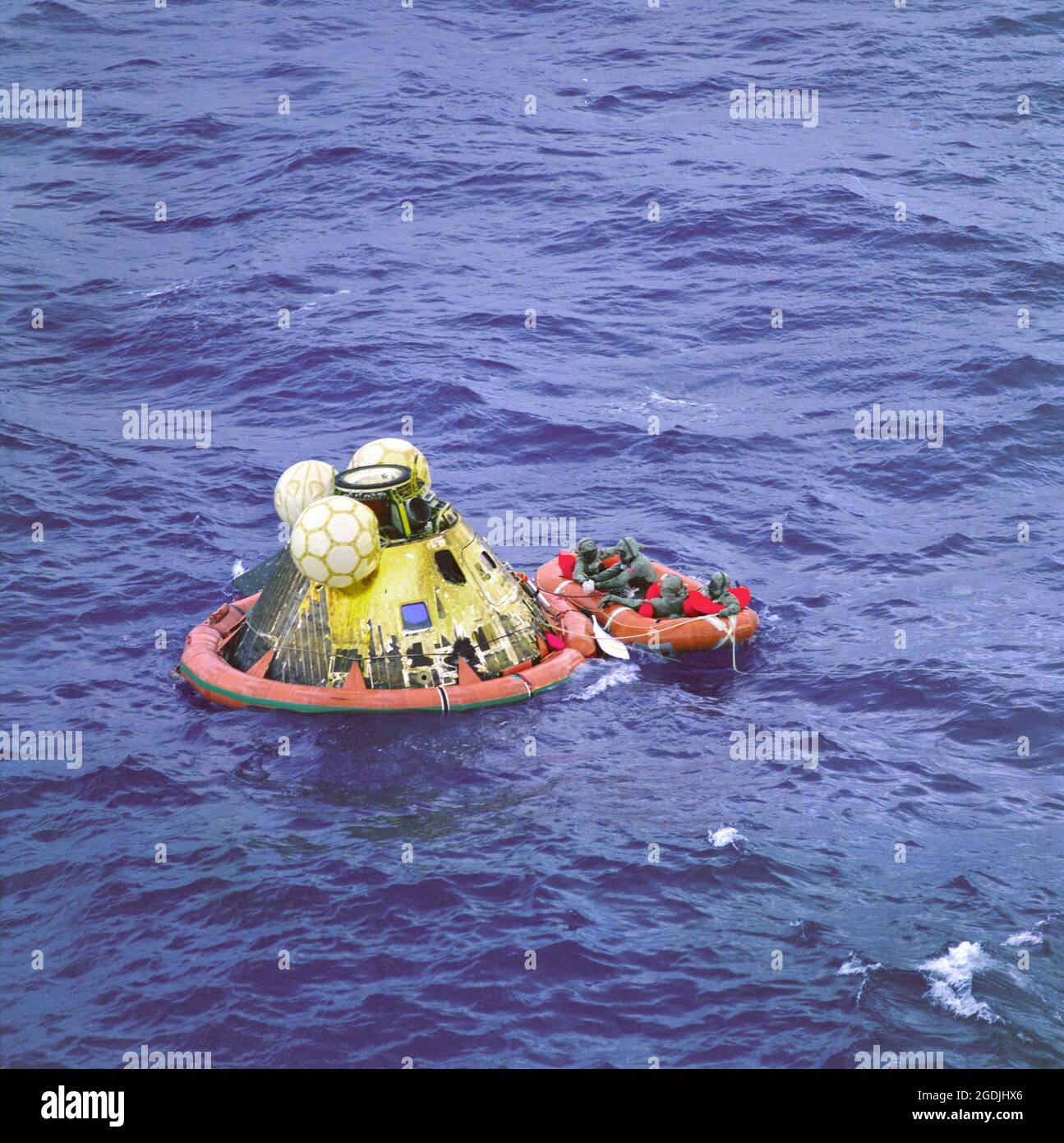The Apollo 11 crew await pickup by a helicopter after the historic Apollo 11 lunar landing mission. They are in a raft next to the Apollo capsule after splashdown. Stock Photo
