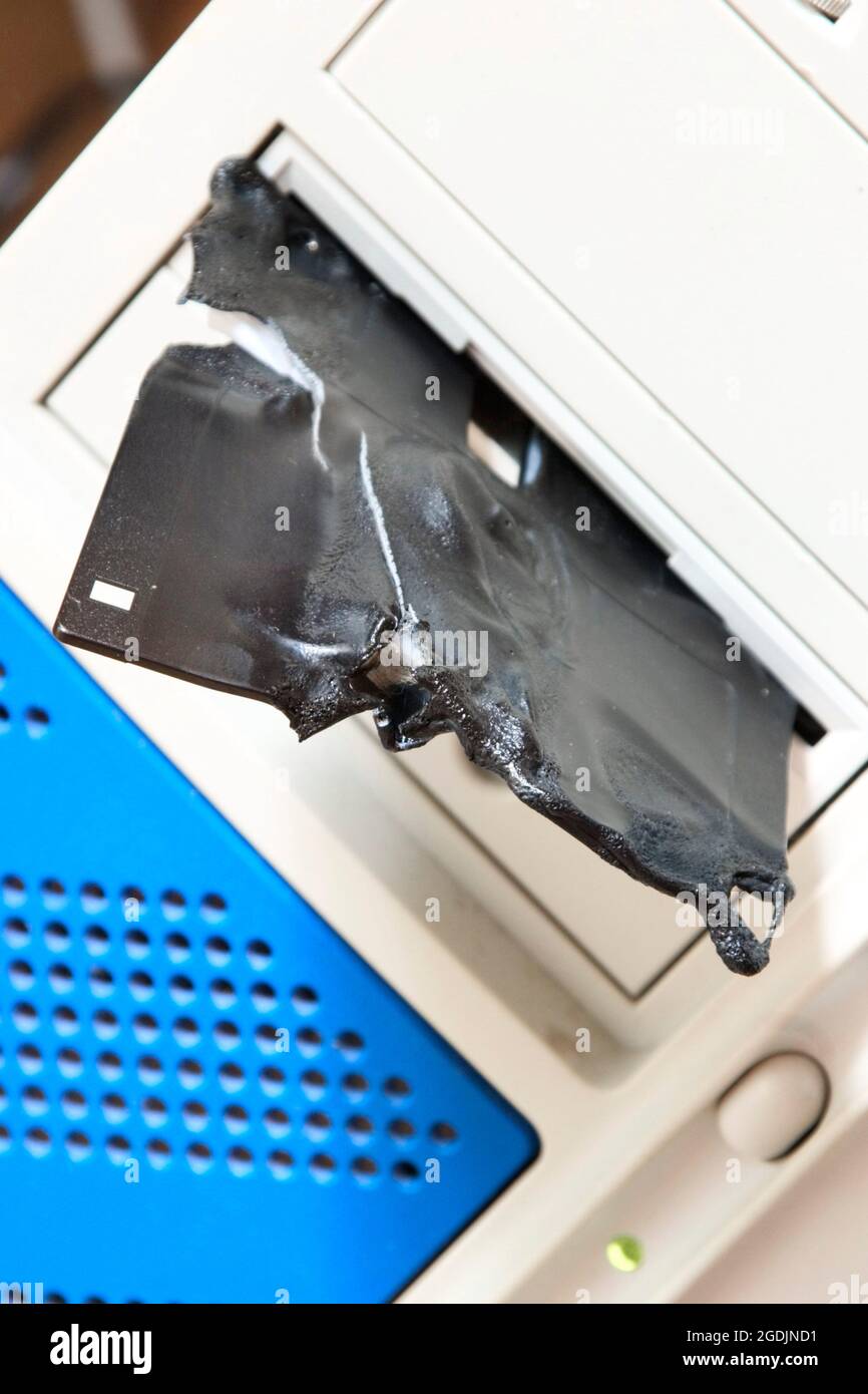 melted and broken floppy disk in a drive Stock Photo