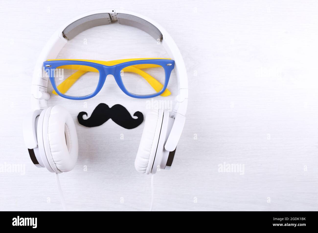 Glasses, mustache and headphone forming man face on color background