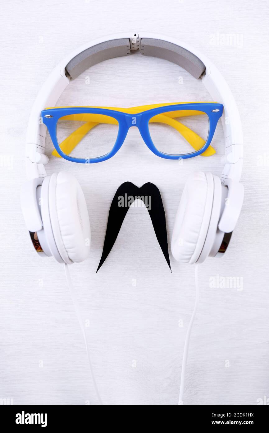 Glasses, mustache and headphone forming man face on color background
