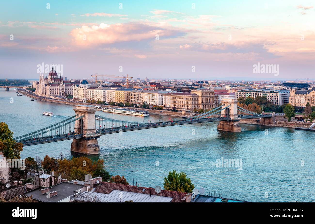The river Danube with tourboats, the Chain Bridge and the Pest skyline in Budapest, Hungary. Photo taken in the evening, from Buda Castle. Stock Photo