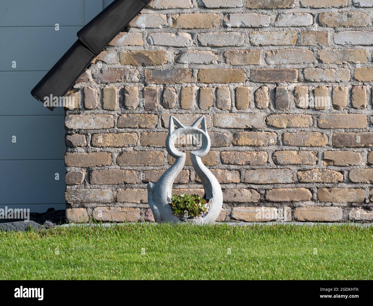 Concrete silhouette of a large cat with flowers as garden decoration Stock Photo