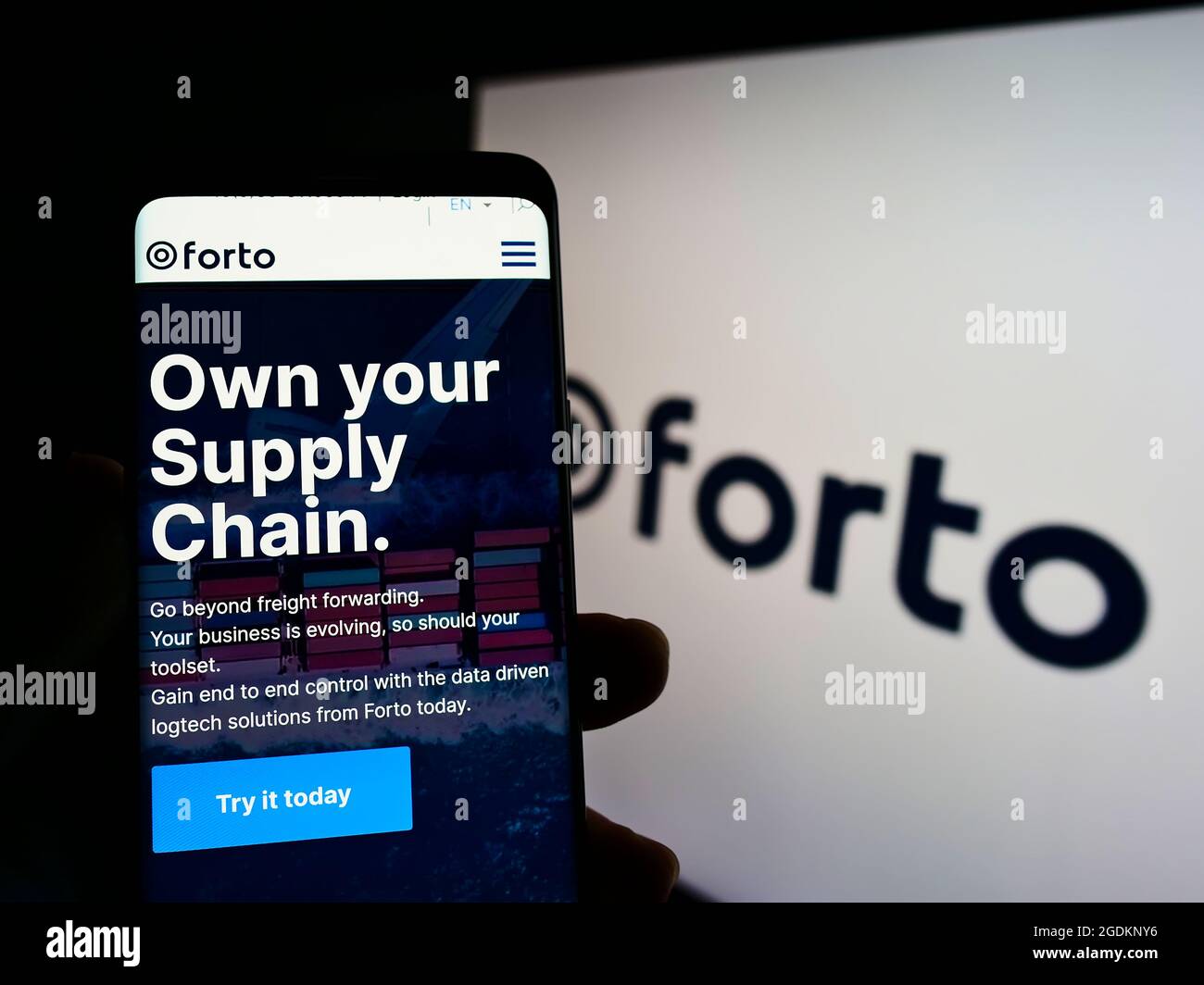 Person holding smartphone with website of German logistics company Forto GmbH on screen in front of business logo. Focus on center of phone display. Stock Photo