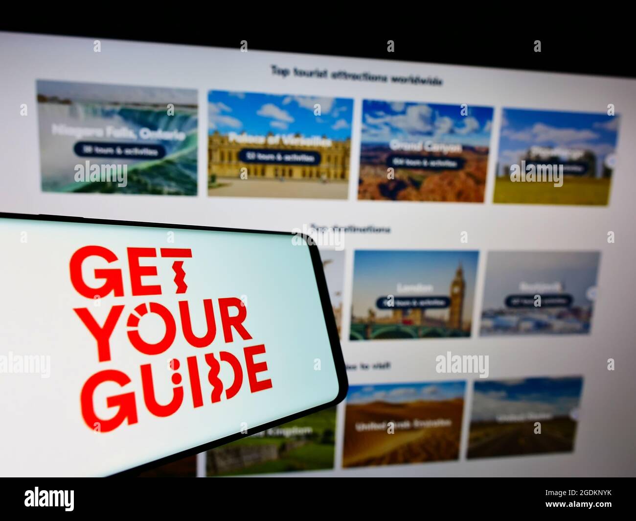 Cellphone with logo of German travel company GetYourGuide Deutschland GmbH on screen in front of website. Focus on center-right of phone display. Stock Photo