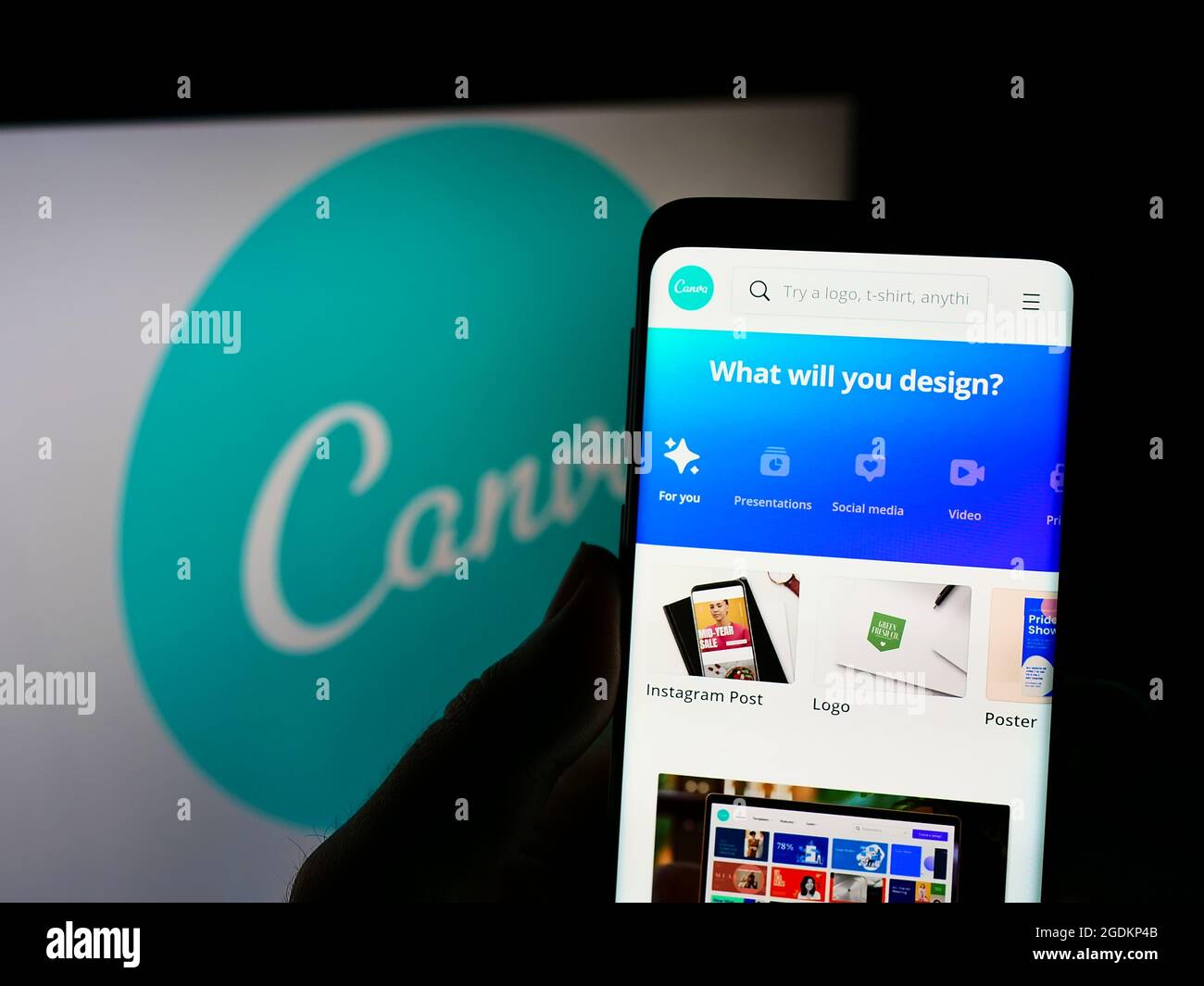 Person holding cellphone with webpage of Australian graphic design company Canva on screen in front of logo. Focus on center of phone display. Stock Photo