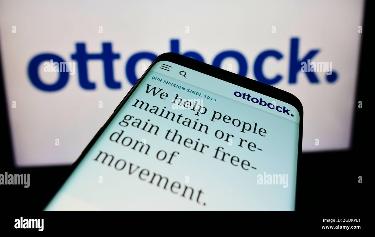 Mobile phone with website of German prosthetics company Ottobock SE Co. KGaA on screen in front of logo. Focus on top-left of phone display. Stock Photo