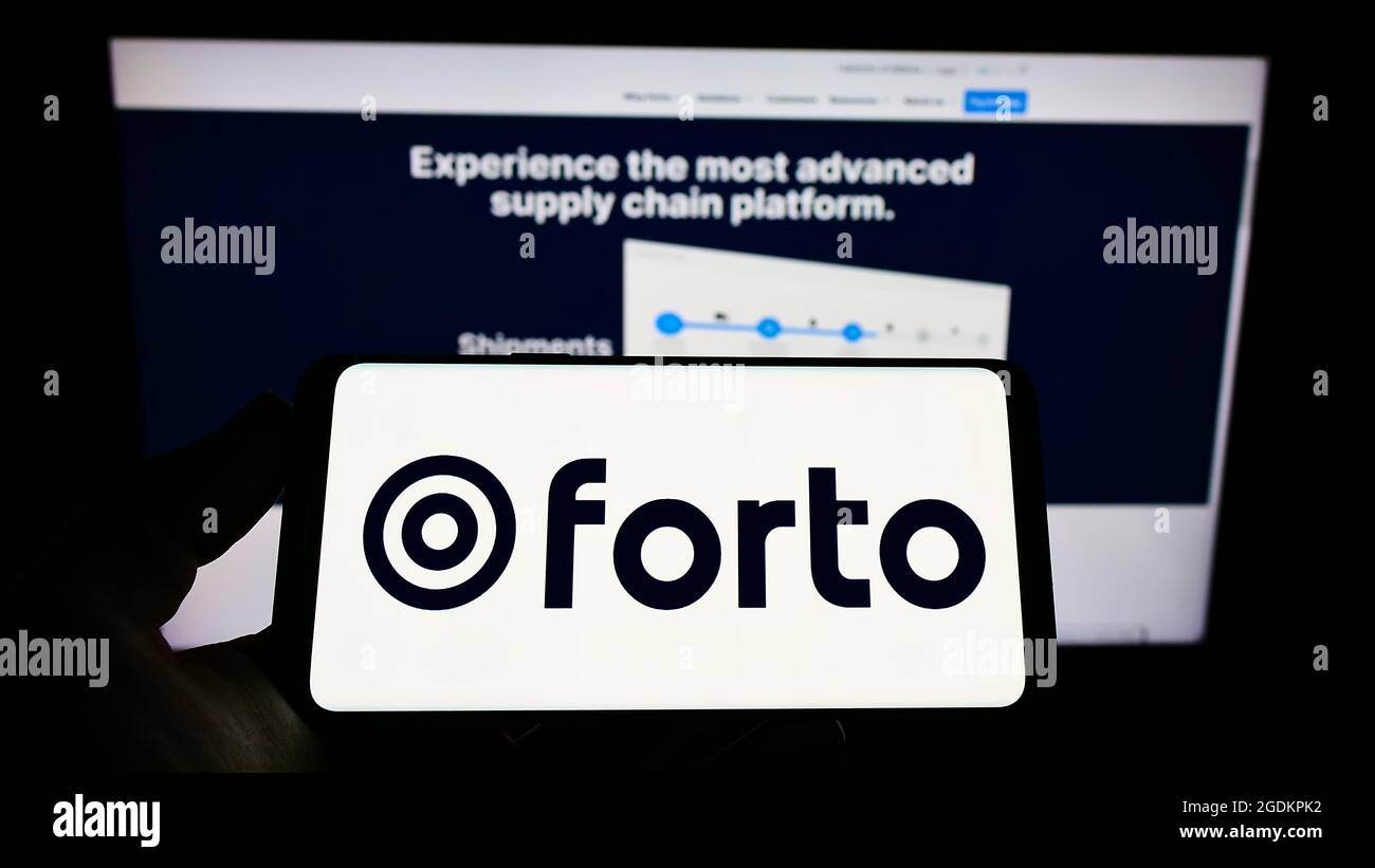 Person holding mobile phone with logo of German logistics company Forto GmbH on screen in front of business web page. Focus on phone display. Stock Photo