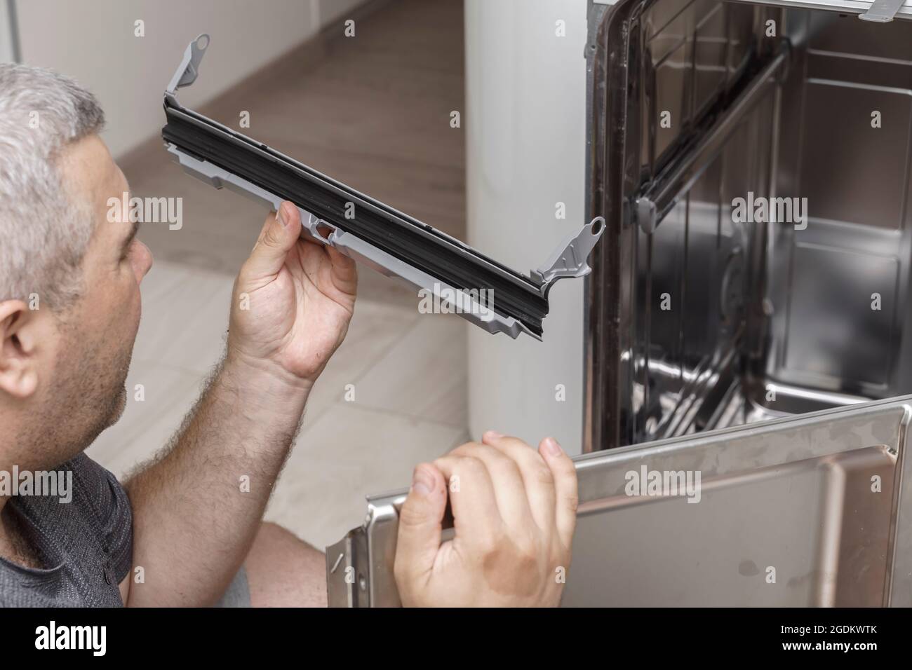 dishwasher repair. a man installs a new rubber seal to replace the damaged Stock Photo Alamy