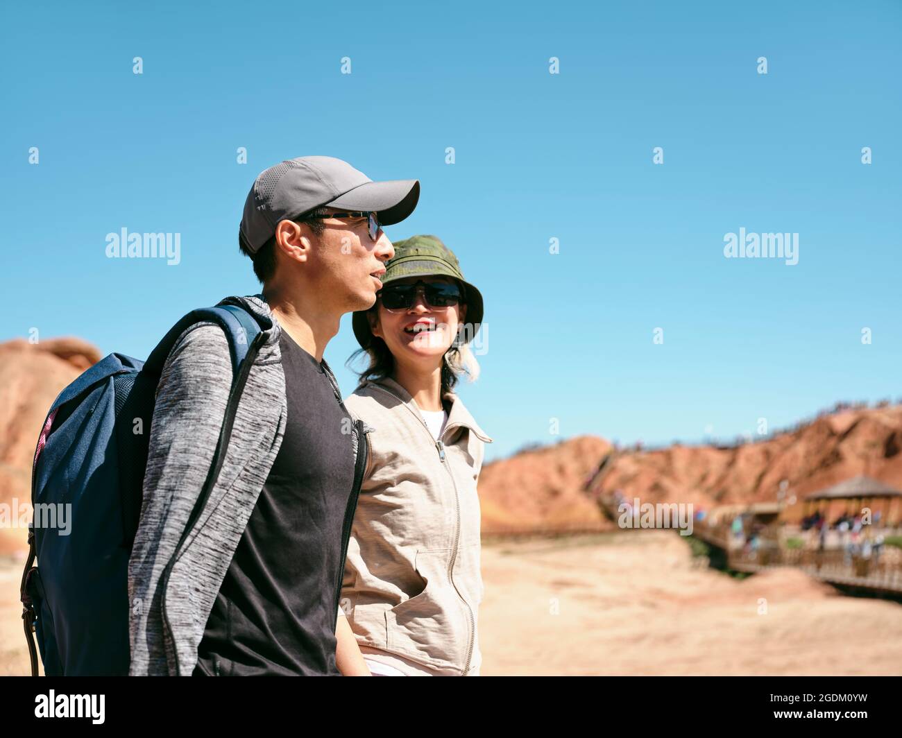 asian couple tourists backpackers walking chatting in national geological park, side view Stock Photo
