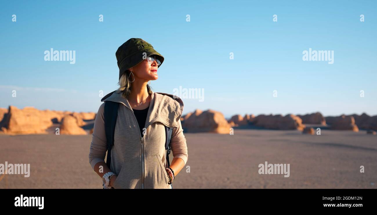 outdoor portrait of an asian woman touris with yardang landforms at sunset in the background Stock Photo